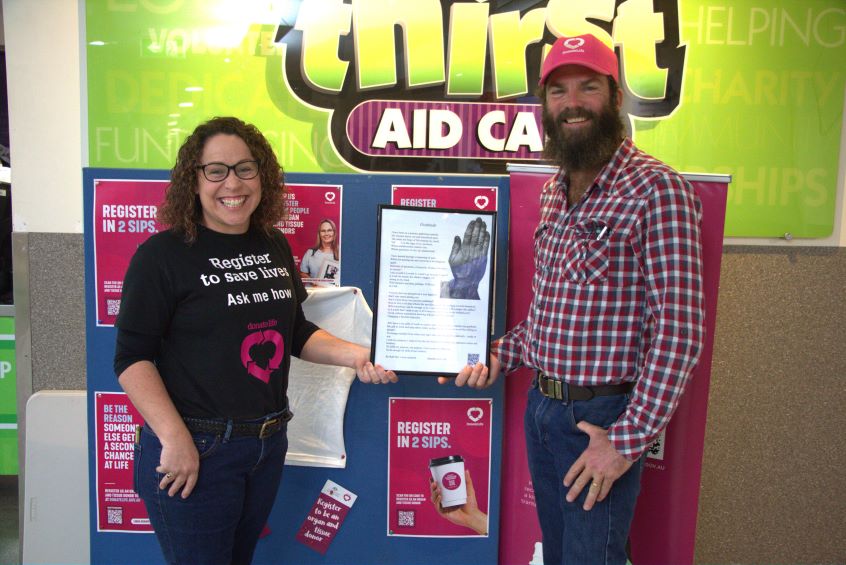 Woman and man standing next to posters about organ donation
