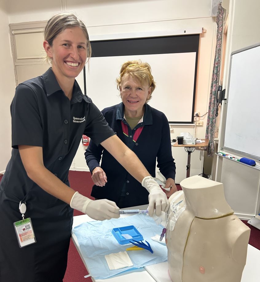 Two nurses demonstrating procedure on mannequin