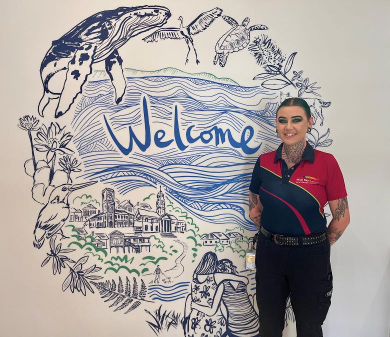 Female hospital employee standing in front of a welcome sign at a mental health unit