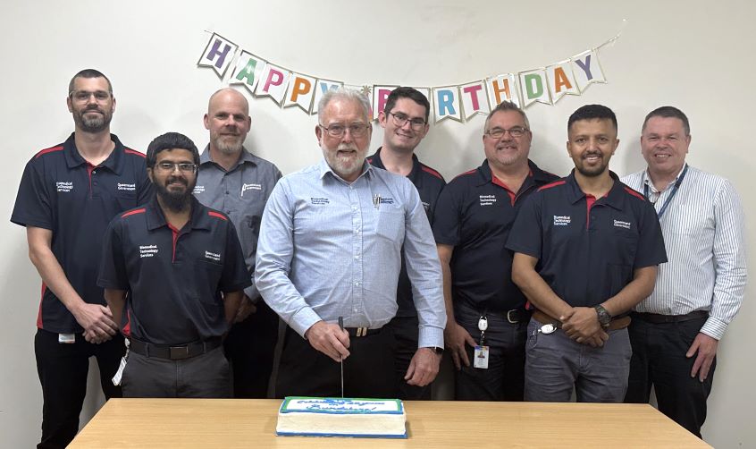 Group of technicians celebrating 10 years of service cutting a cake