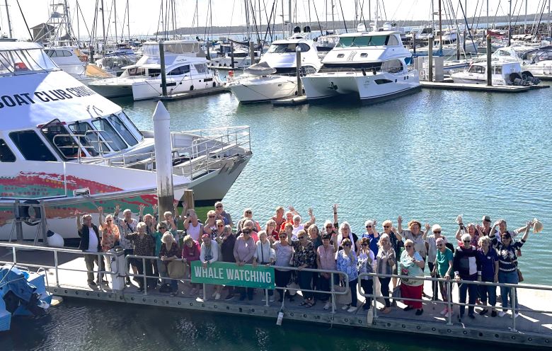 Group of people standing on a wharf in front of cruise boats