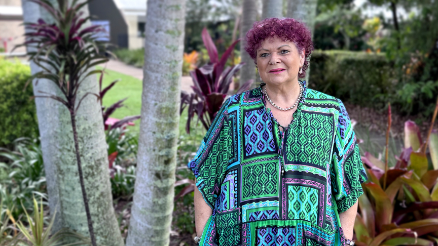Image of woman standing in front of trees smiling at camera