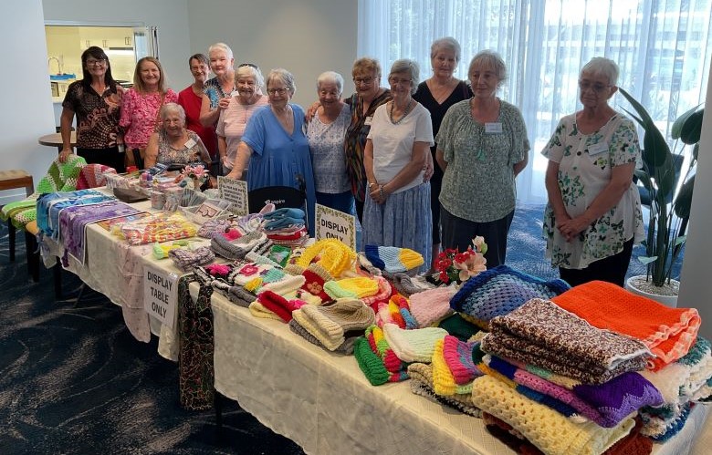 Community members gathered in front of a table of handcrafted items