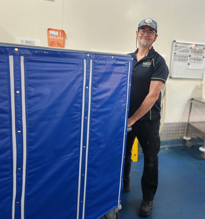 Male hospital catering worker pushing food trolley