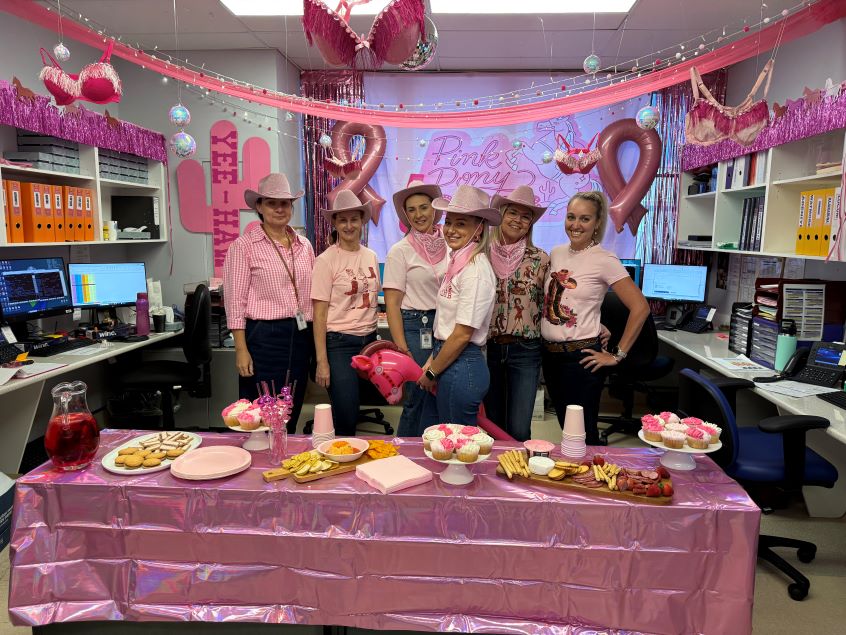 Group of healthcare workers dressed in pink within a pink decorated workspace.