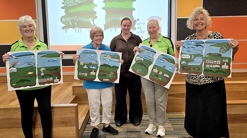 Image of four hospital volunteers holding up collage artwork with local artist