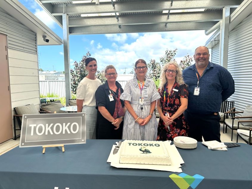 Group of healthcare workers standing behind table with a cake