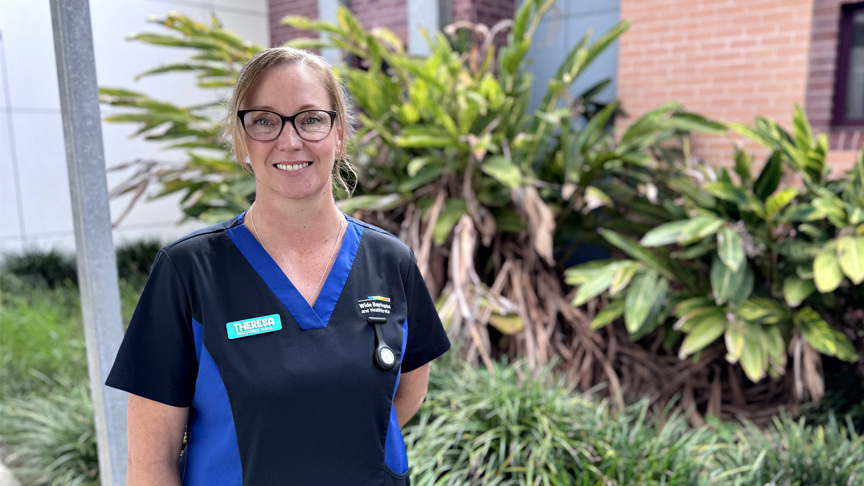 Female nurse standing in front of building and plants