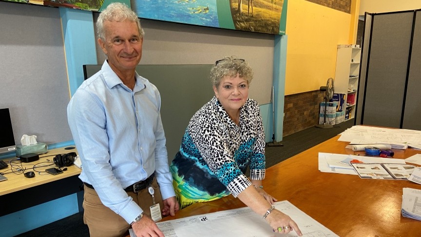 Photo of man and woman at a table pointing at design layouts