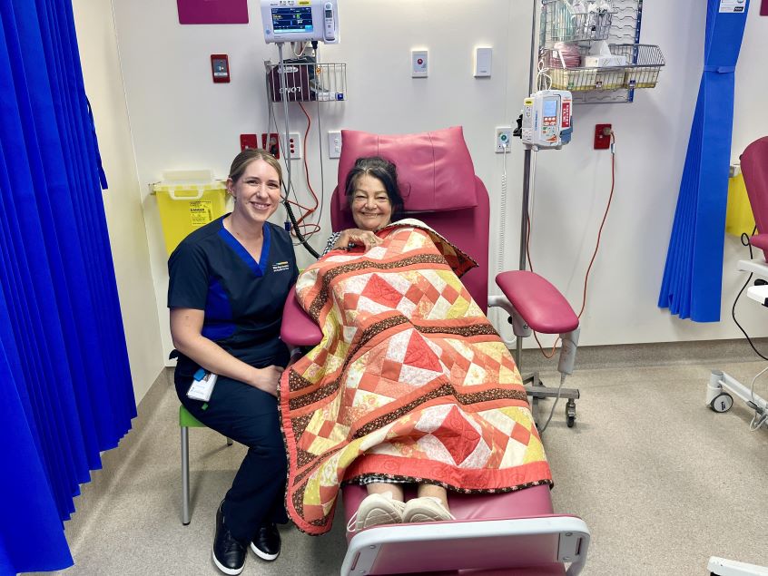 Nurse seated next to woman with quilted blanket