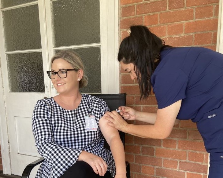 Woman receiving vaccination in arm from nurse