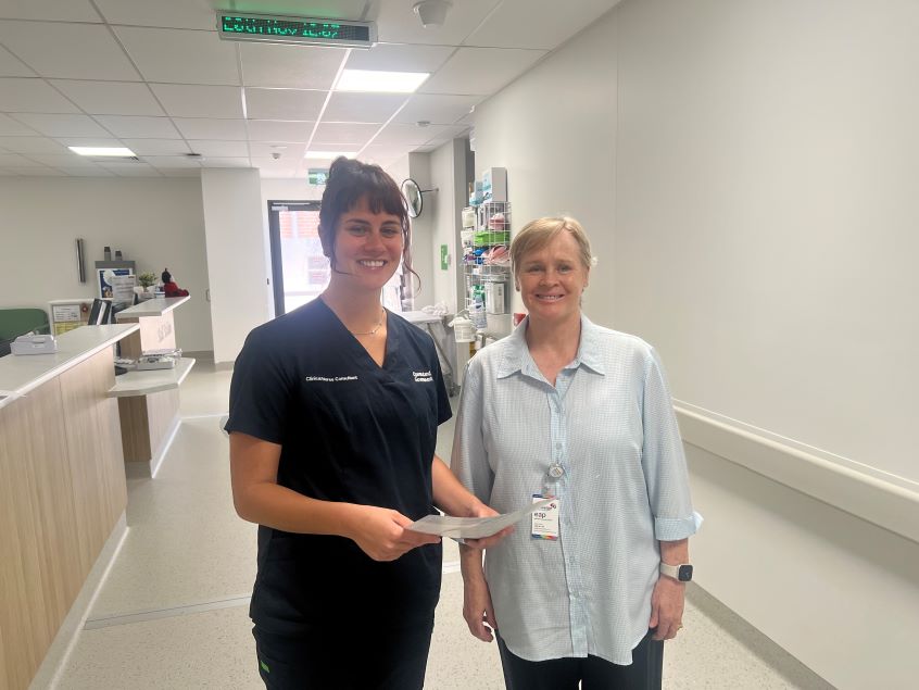 Healthcare worker standing next to stroke volunteer in hospital corridor
